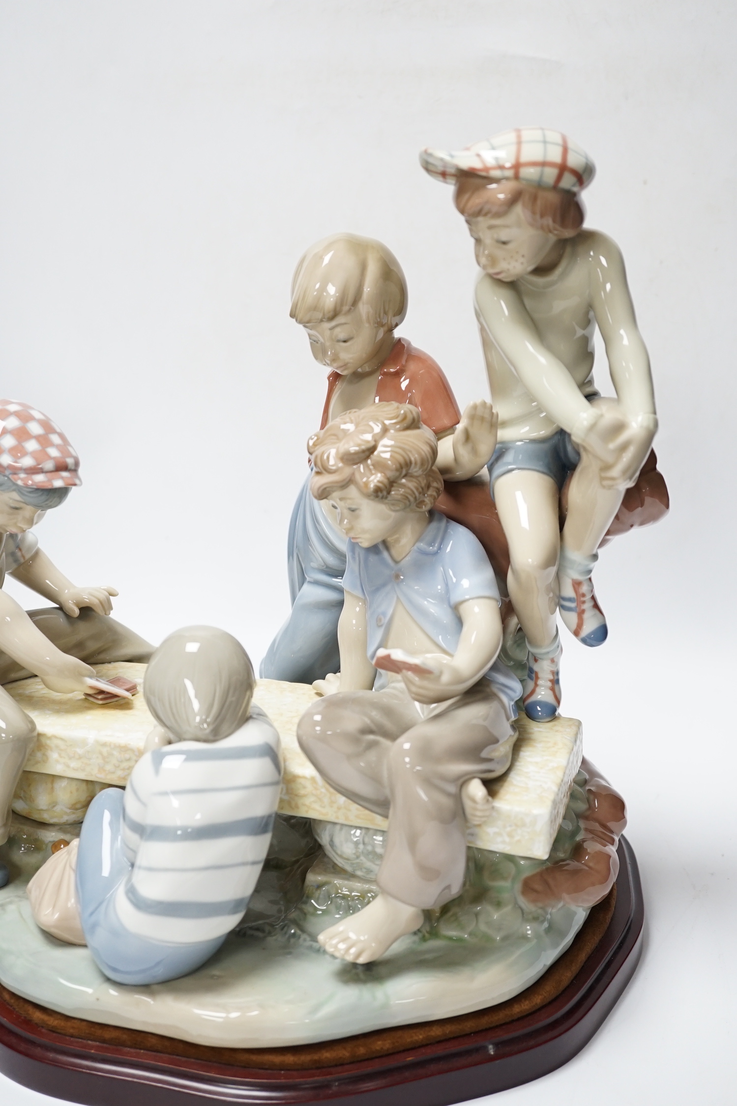 A large Nao figure group on stand of five boys sitting around a table playing cards, 33cm